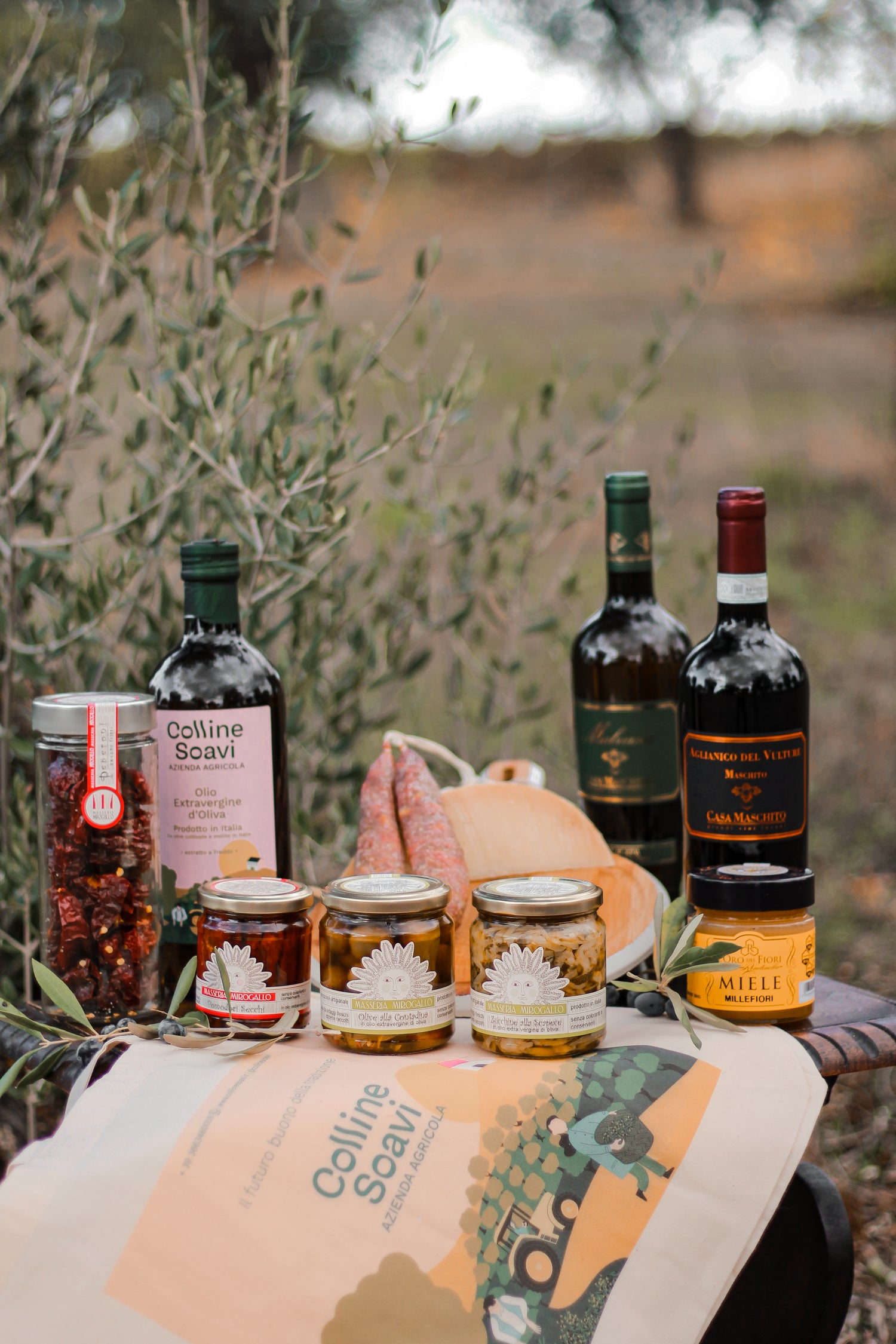Bottiglie di olio e vino e barattoli di verdure sott'olio su un tavolino di legno